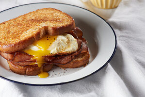 Fired egg sandwich with sliced ham and a yolk drip