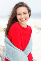 A young brunette woman wearing a red jumper with a grey woollen shawl