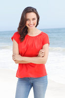 A young brunette woman wearing a red blouse and jeans