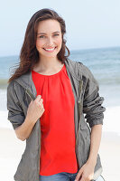 A young brunette woman wearing a red blouse, a grey windbreaker