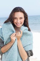 A young brunette woman wearing a grey windbreaker and a woollen shawl