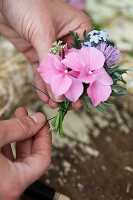 Tying a posy of hydrangea florets, forget-me-nots and chive flowers