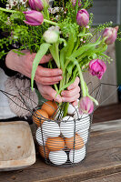 Blumenstrauß mit Tulpen, Hirtentäschel und Australischer Wachsblume im Metallkorb mit Eiern