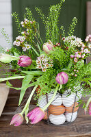 Bouquet of tulips, shepherd's purse and Australian waxflowers in wire basket with eggs