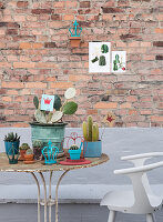 Rusty metal table with cacti and vintage decorations in front of a brick wall