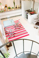 A view from a spiral staircase of a kitchen with a glass table and transparent chairs