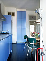 Retrostühle und Designerleuchte in der Wohnküche mit blauen Fronten