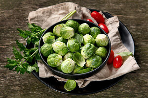 Rosenkohl, Tomaten und Petersilie auf Holztisch