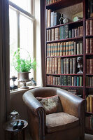 Vintage leather armchair next to bookcase in corner