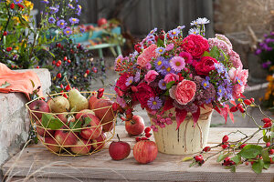 Autumn bouquet of roses, asters, stonecrop, rose hips and spindle, basket with apples and pears