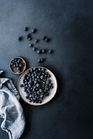 Fresh blueberries on plates in front of a dark background