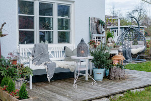 Terrasse mit Tannenbaum, Windlichtern und Bank mit Decke, Fell und Kissen