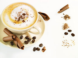 Tasse Cappuccino mit Schokoladenröllchen und Kaffeebohnen