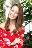 A young woman wearing a red floral-patterned Carmen blouse