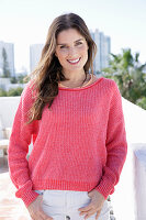 A young woman wearing a fuchsia jumper and white jeans