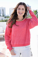 A young woman wearing a fuchsia jumper and white jeans