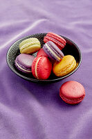 Macarons in a black bowl on a purple background