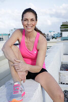 Frau in Sportbekleidung auf der Terrasse sitzend