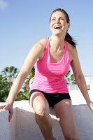 A happy woman on a terrace wearing sports gear