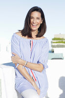 A brunette woman wearing a blue-and-white striped Carmen blouse