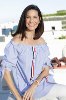 A brunette woman wearing a blue-and-white striped Carmen blouse