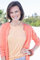 A young woman wearing an apricot top and cardigan