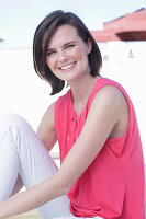 A young woman wearing a pink top and white white trousers