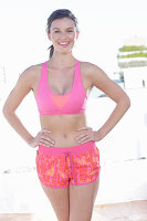 A young woman wearing a pink sports bra and patterned shorts