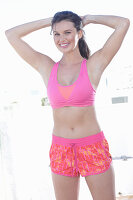 A young woman wearing a pink sports bra and patterned shorts