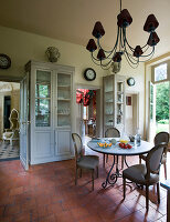 Glass-fronted cabinet, round table and upholstered antique chairs in breakfast room