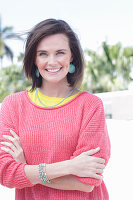 A young woman wearing large earrings, a fuchsia jumper and a yellow top