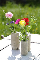 Ranunculus, floss flower and anemones in handmade concrete vases