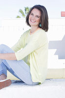 Junge Frau in apricotfarbenem Top, gelbem Pulli und Jeans