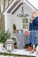 Woman standing on deck of cosily decorated arbour in wintry garden