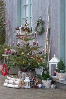 Nordmann fir decorated with Christmas tree balls, fairy lights and candles, stars, lanterns and birch trunks as decoration