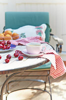 Tasse Kaffee, Kirschen und Muffins auf sommerlichem Gartentisch