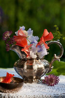 Posy of sweet peas, astrantia and lady's mantle in silver jug