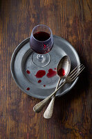 Red wine glass on a metal plate with cutlery