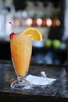 Rum punch on a bar with an orange slice and marschino cherry garnish
