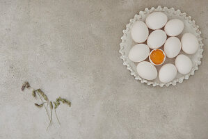 White eggs on a ceramic plate with grass flowers