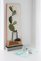 Glass paperweights on pale blue paper below picture of cactus