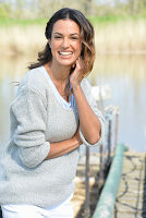 A young woman wearing a grey jumper near river