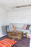 Old trunk used as coffee table in front of bench in living room of wooden house