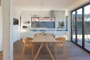 Open-plan cooking and dining area with modern kitchen and wooden dining table and chairs