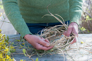 Woman winds wreath as an Easter basket made of grass