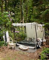 Canopy bed with black-and-white accessories in woodland clearing