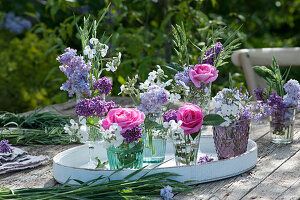 Kleine Sträuße aus Rosen, Flieder, Nachtviole und Gräsern auf Holztablett