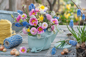 A colorful bouquet in a teapot: daisies, primroses, grape hyacinths, daffodils and twigs