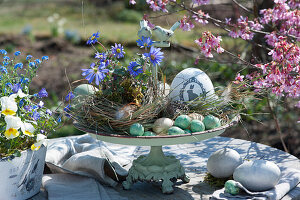Etagere with ray anemone and Easter eggs as a table decoration and Easter basket