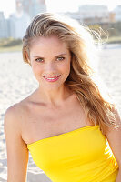 Blonde Frau in gelbem Bandeau-Kleid am Strand